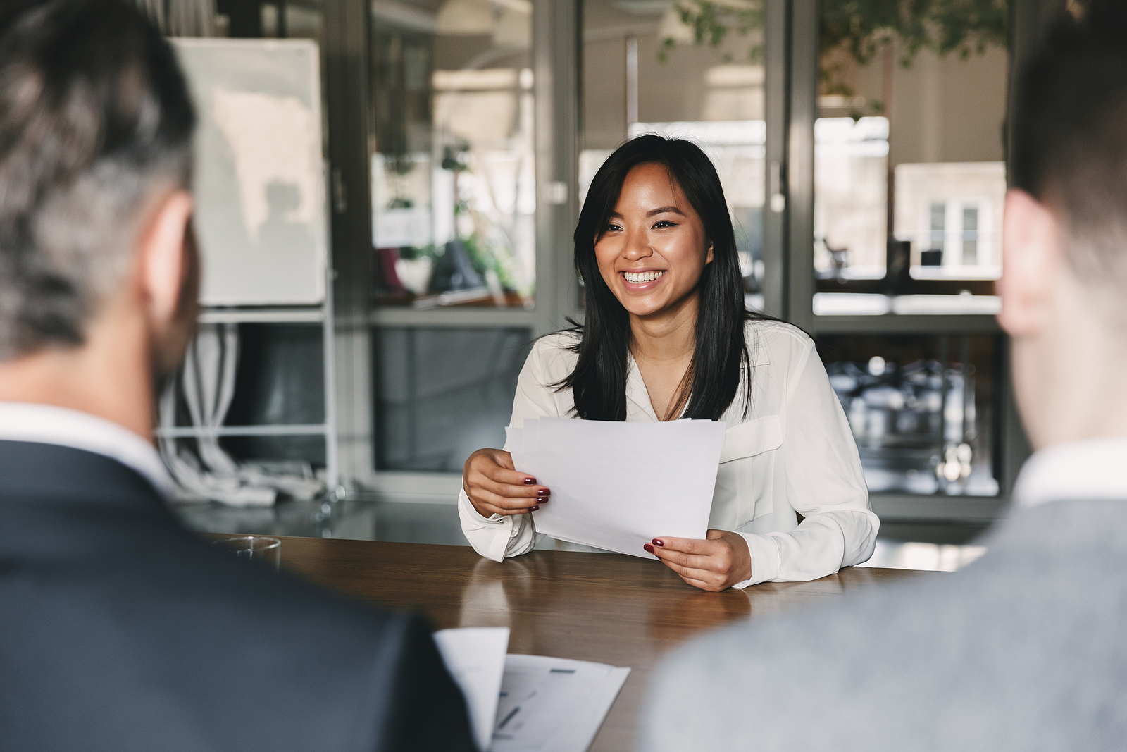 woman smiling and holding resume, while sitting in job interview